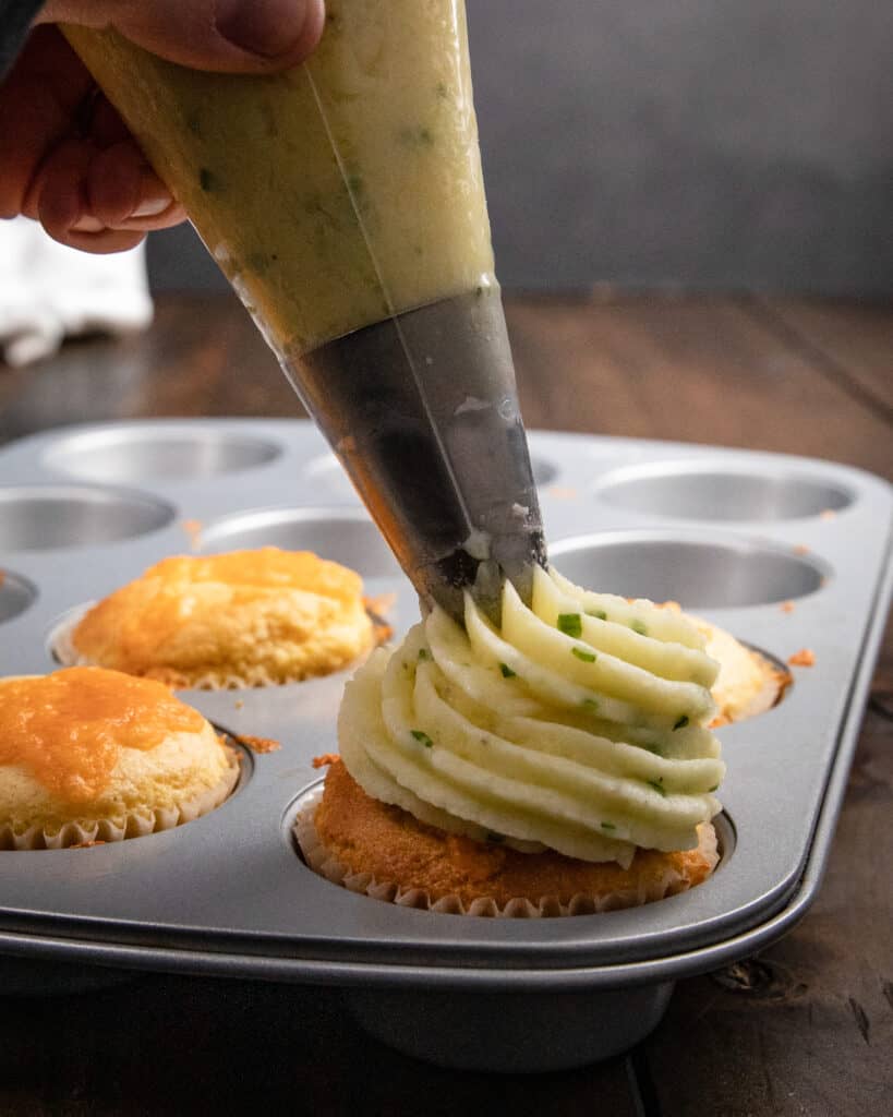 Piping mashed potatoes onto cornbread muffins