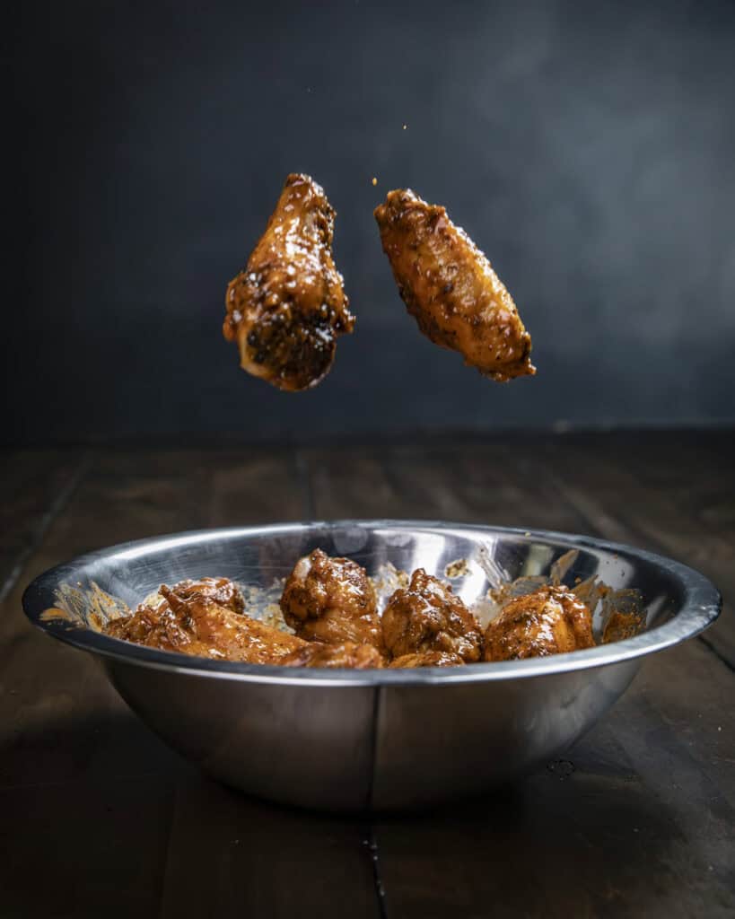 Buffalo wings being tossed in sauce.