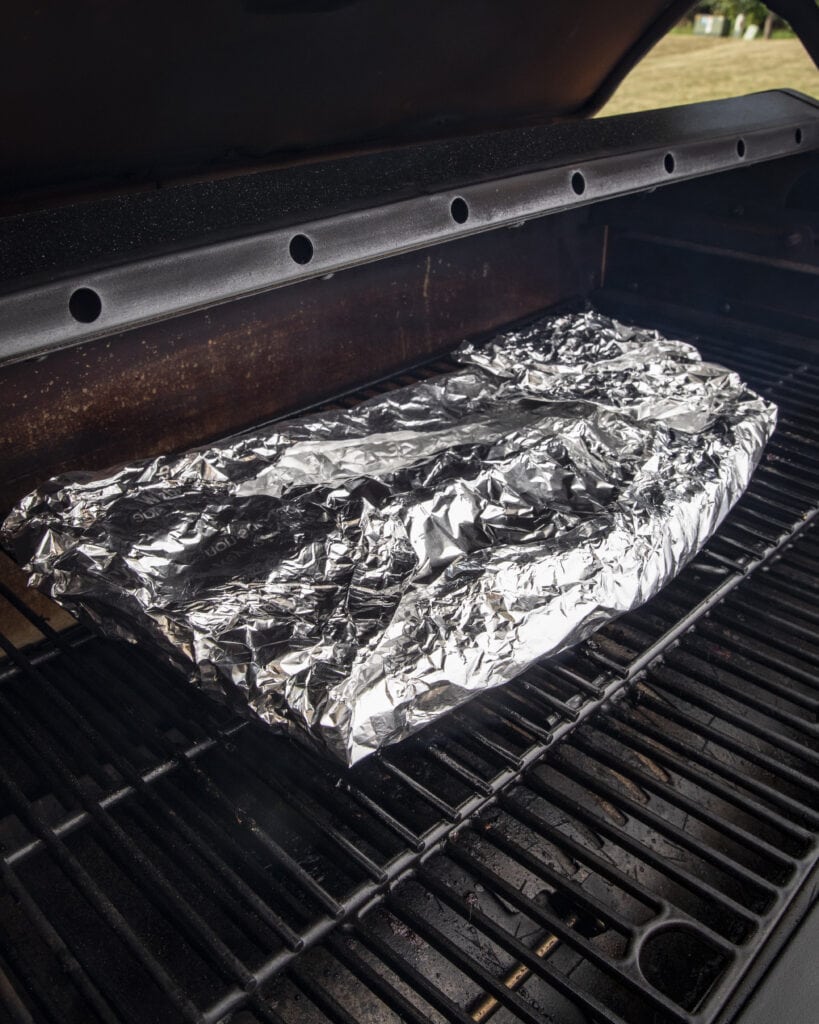 Baby back ribs wrapped in foil on the smoker.